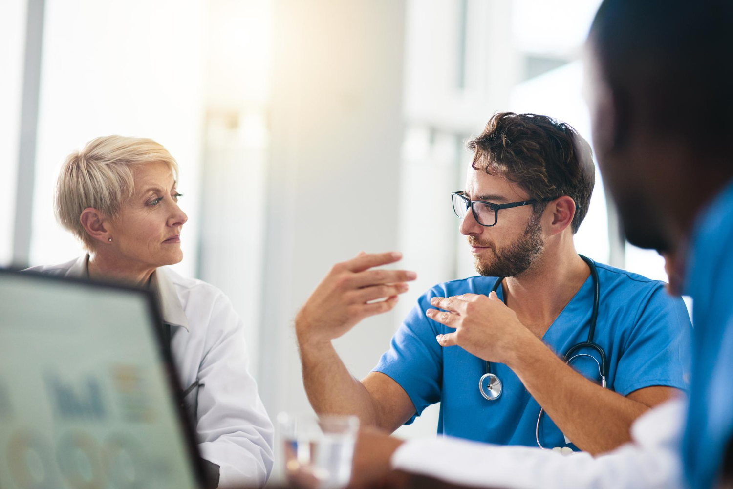 Healthcare provider in scrubs consulting with a patient using a tablet