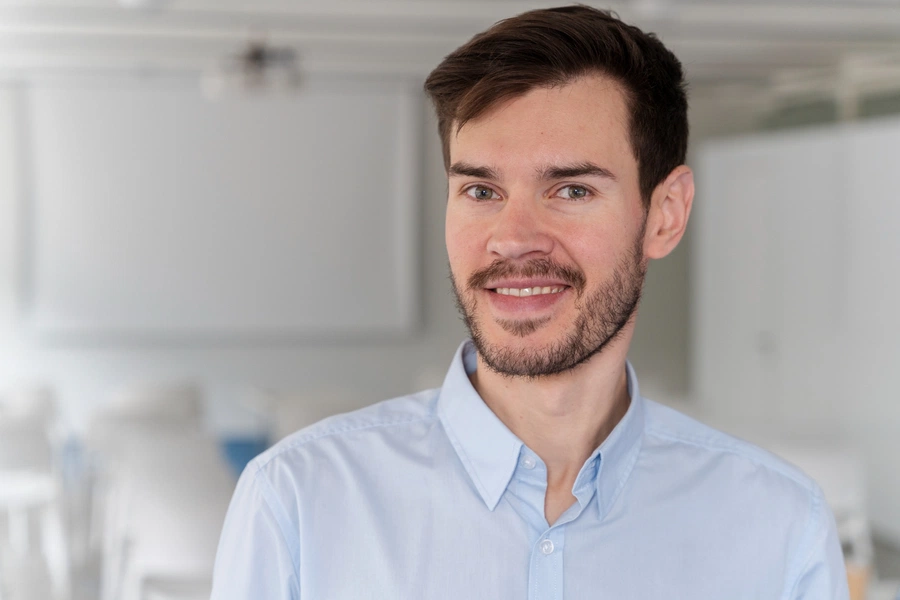 Young male behavioral health professional smiling in office setting
